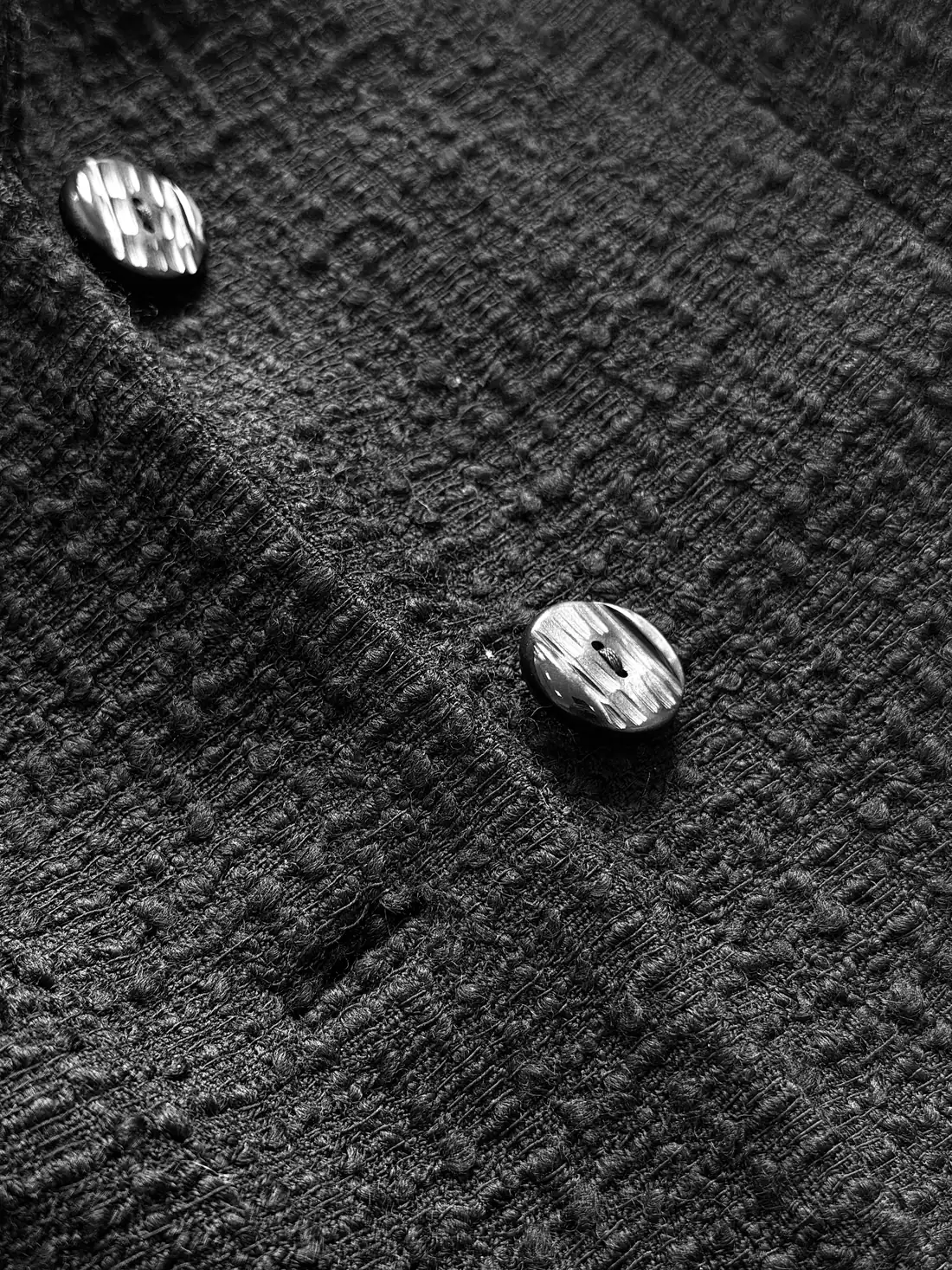 Two buttons on black bouclé.