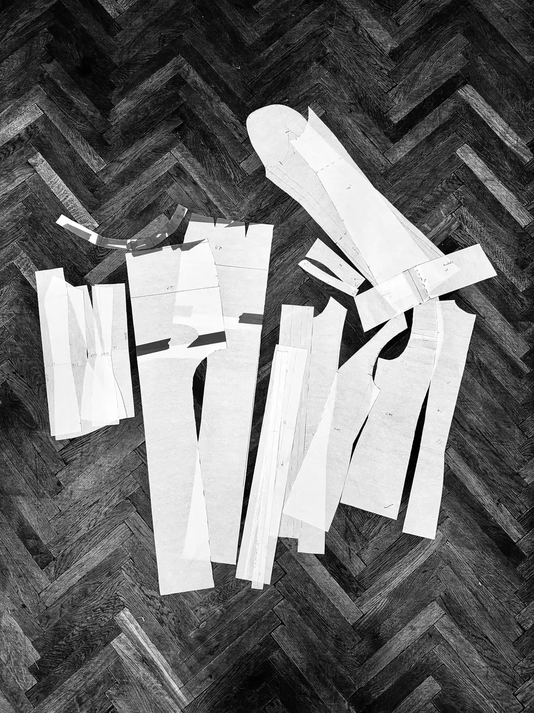 Paper pattern pieces laid out on a parquet floor.