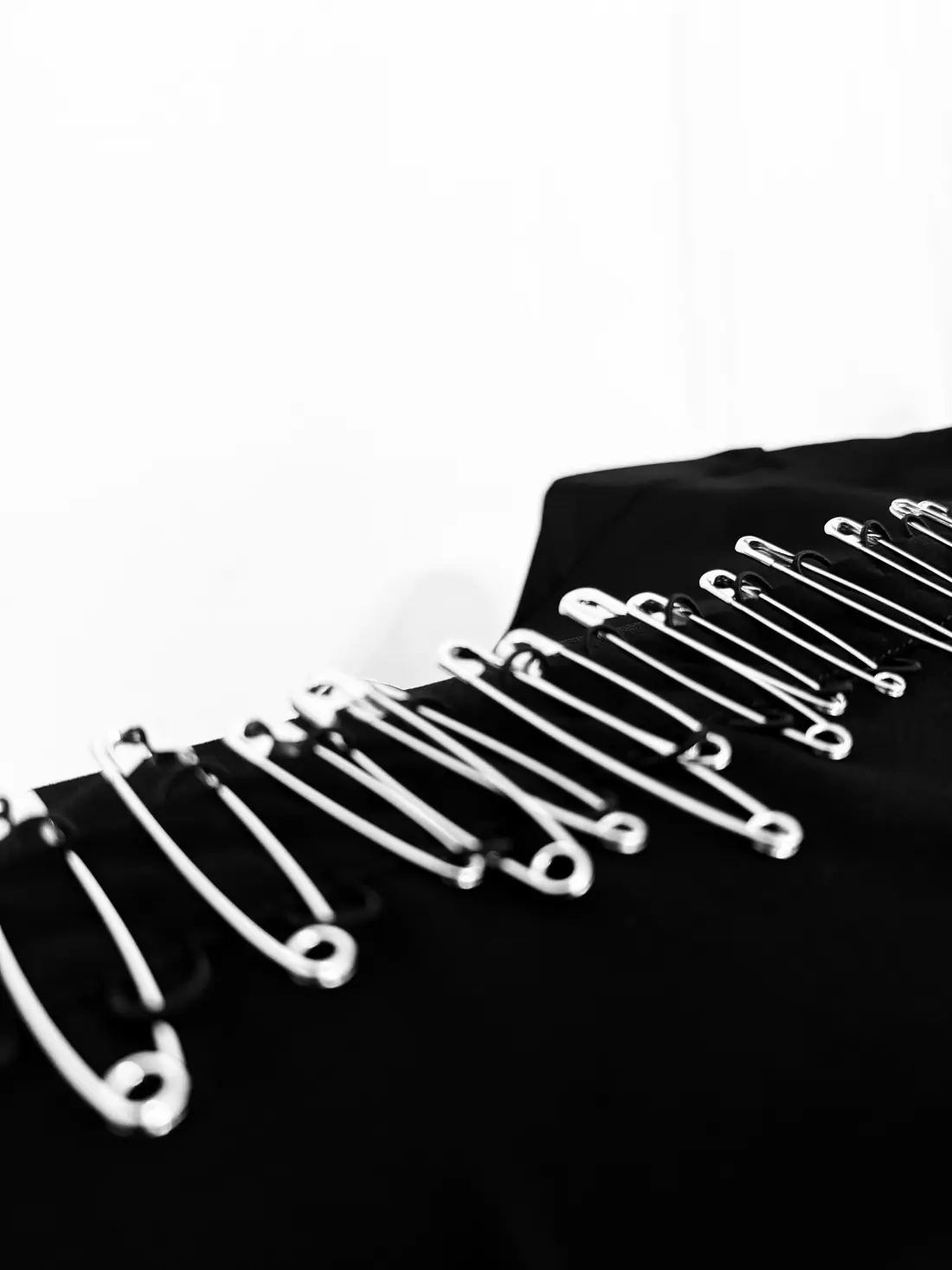 Safety pins lined along a black placket.
