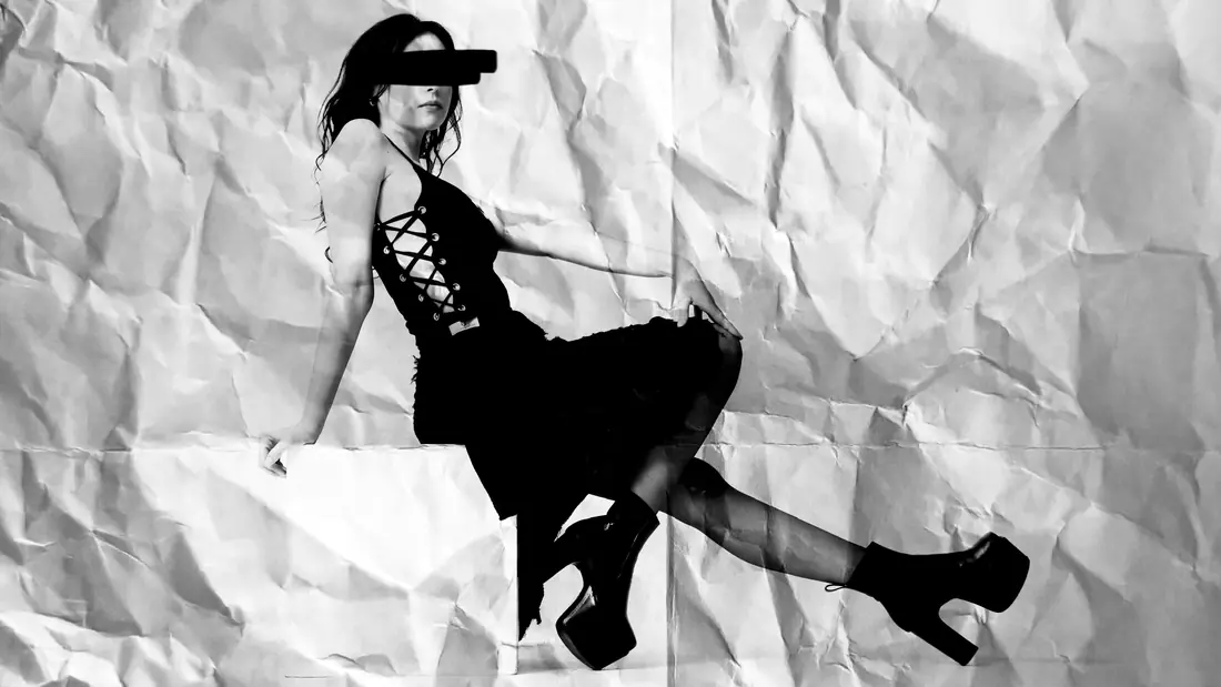 Seated on a white block against crumpled paper in the Core top, legs stretched out in platform boots.